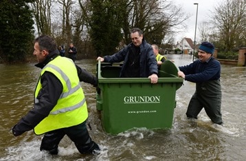 Photo caption: One resident is rescued in a Grundon recycling bin as floods hit Egham, Surrey (photo: Andrew Parsons)
